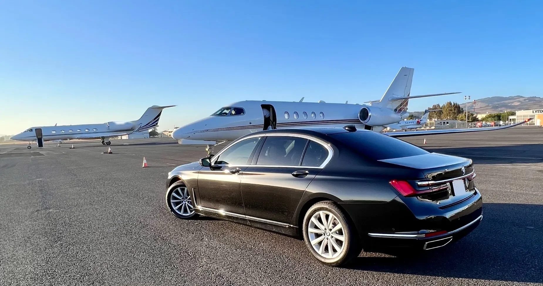 Premium sedan in front of private aircraft